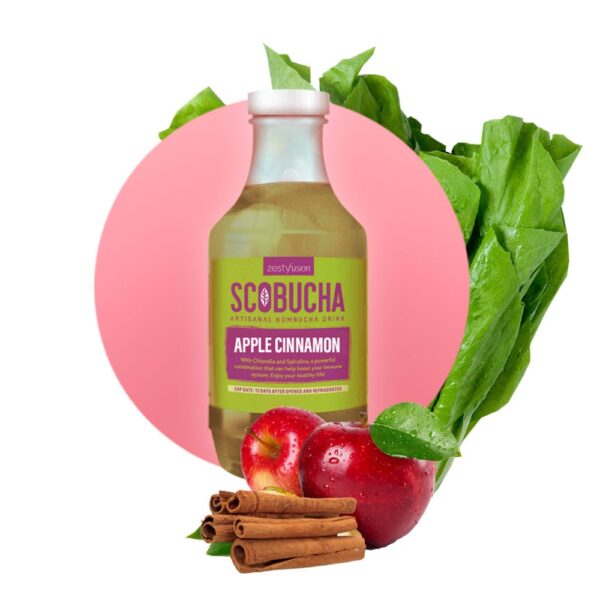 A bottle of apple cinnamon scrbucha next to some apples and a bunch of greens.