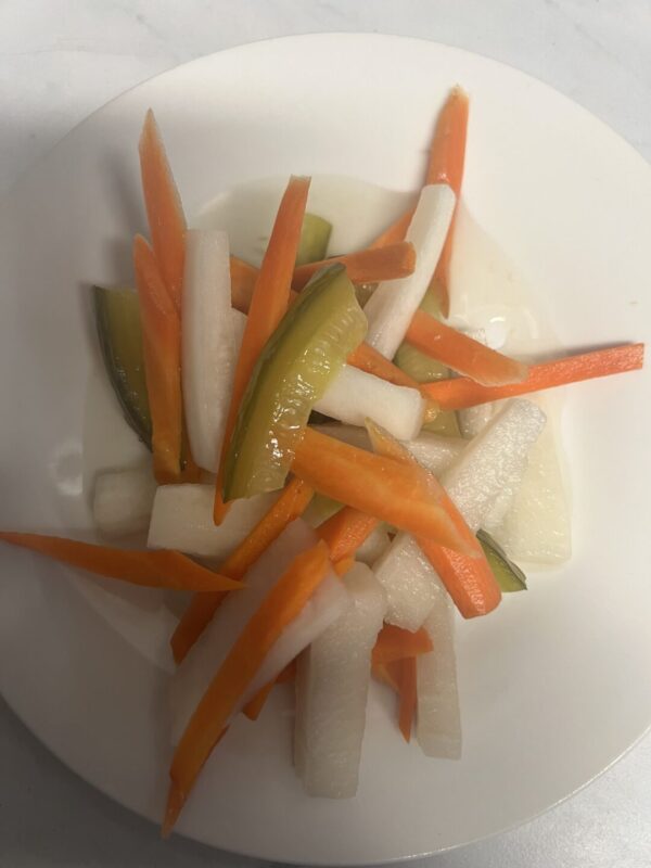 A plate of food with carrots, onions and pickles.